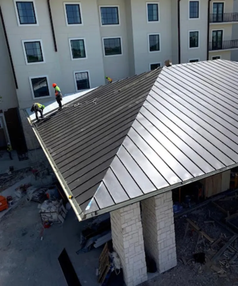 Crew installing standing seam metal roof panels on a commercial project in Davenport